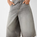 Gray denim shorts worn by a person on a white background