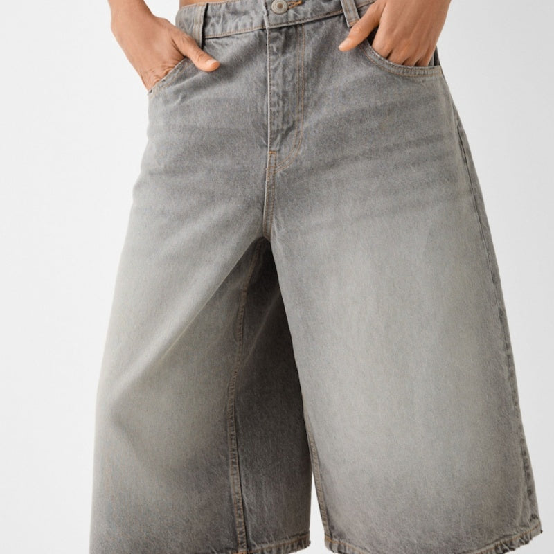Gray denim shorts worn by a person on a white background