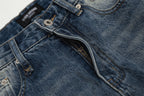 Close-up of blue denim jeans with stitching details on a light gray background