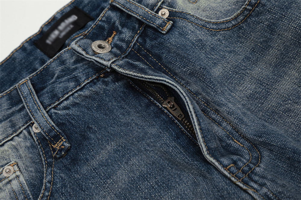 Close-up of blue denim jeans with stitching details on a light gray background