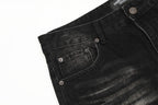 Close-up of black denim jeans with stitching details on a white background