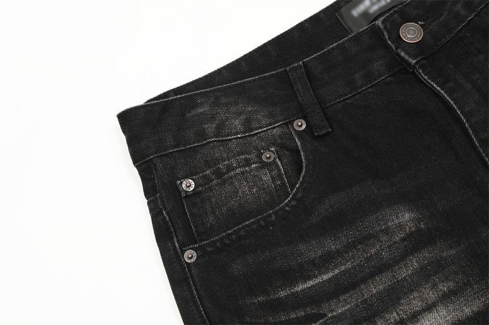 Close-up of black denim jeans with stitching details on a white background
