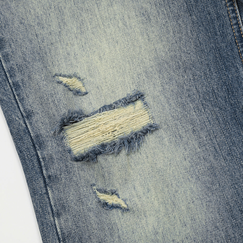 Close-up of a distressed denim fabric with tears and frayed edges.