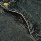 Close-up of a blue denim jacket with a zipper and button detail.