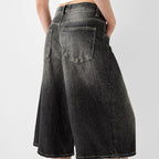 Black denim shorts worn by a person on a light gray background