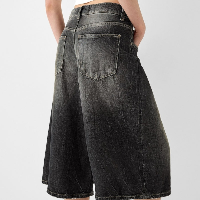 Black denim shorts worn by a person on a light gray background