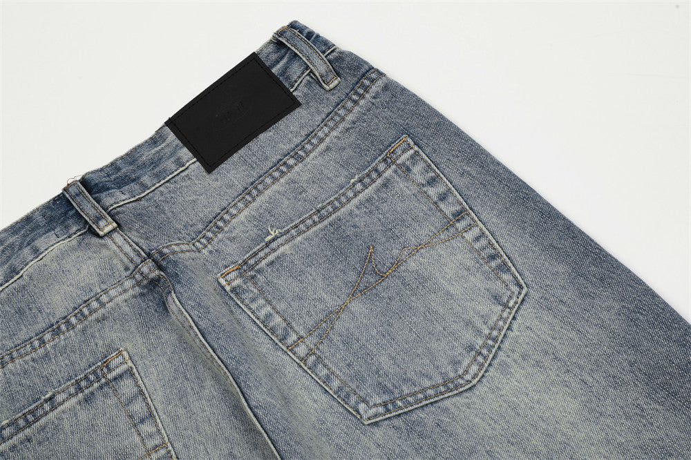 Close-up of a pair of blue jeans with a black label on a light gray background