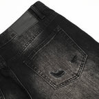 Close-up of black denim jeans with a brand label on a white background