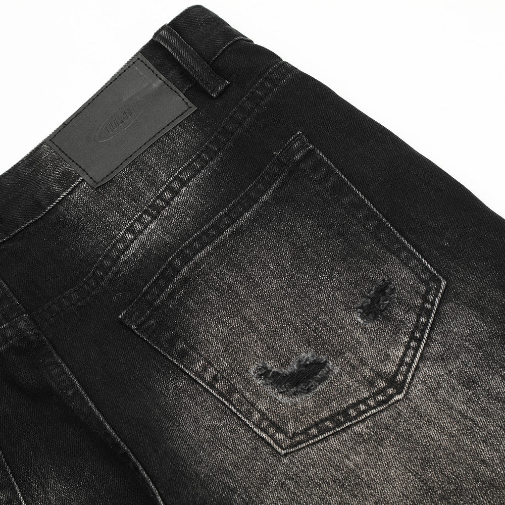 Close-up of black denim jeans with a brand label on a white background
