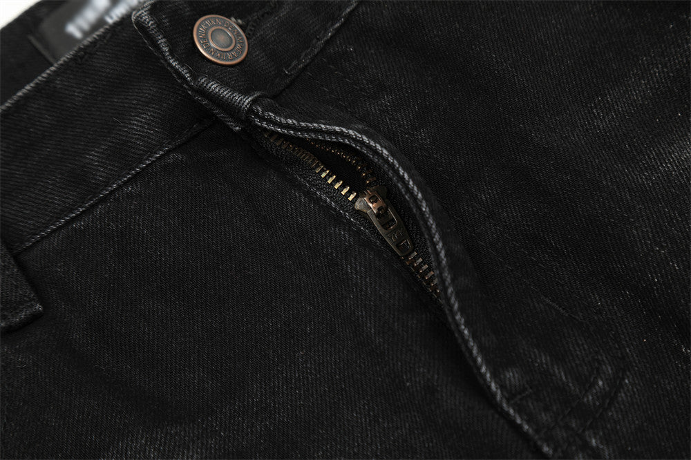 Close-up of a black denim jacket with a zipper and button detail.