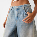 Person wearing light blue jeans with a neutral background